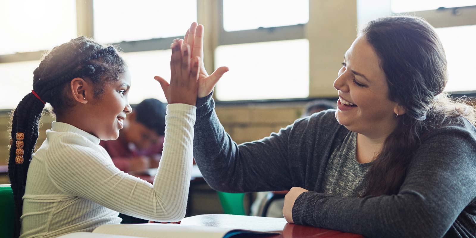 A coach and student celebrating with a high five in class.